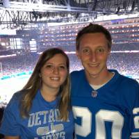 man and woman pose in front of football field
